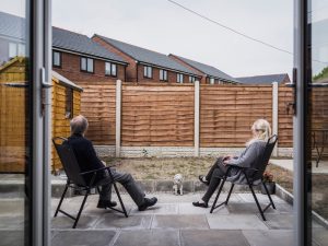Älteres Paar auf Terrasse schaut auf Holzzaun